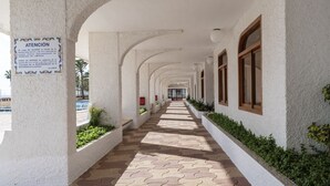 Une allée couverte aux murs blancs et aux fenêtres à cadre en bois, qui mène à l  ’entrée d’un bâtiment.