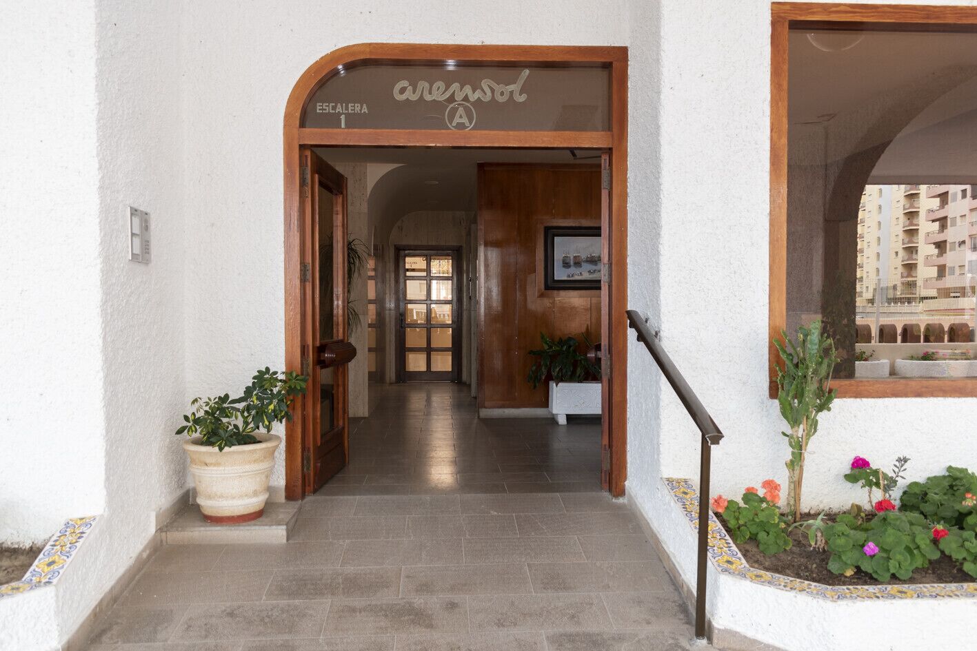 A hotel entrance with a wooden door labeled "arenasol" and a staircase leading to the interior.