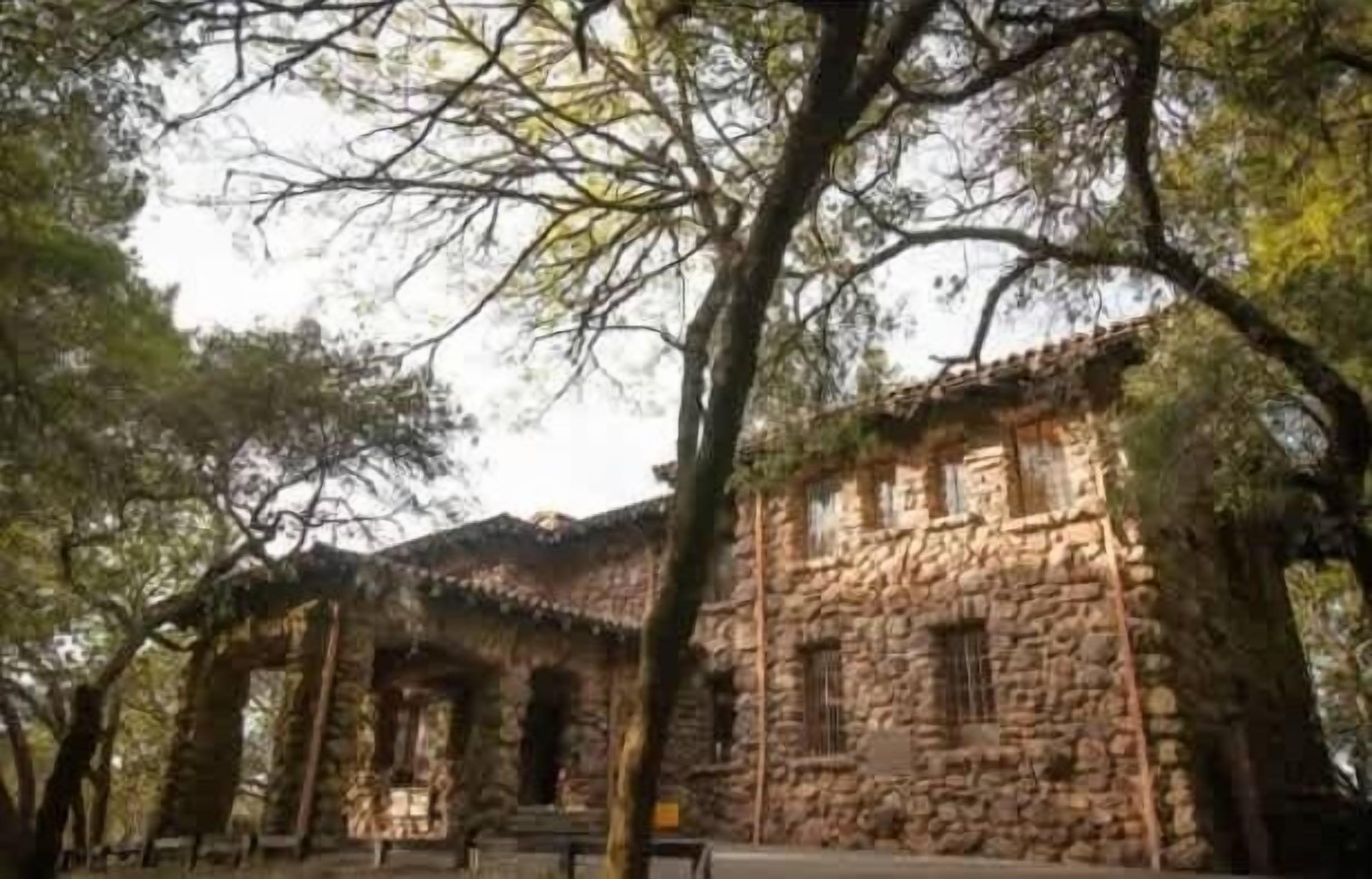A stone building with a traditional architectural style, surrounded by trees.