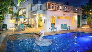 A modern house with a swimming pool, outdoor seating, and a swan float.