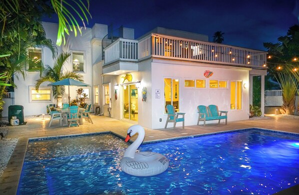 A modern house with a swimming pool, outdoor seating, and a swan float. - 80’s Paradise golf cart, rooftop deck heated pool (Indian Rocks Beach)
