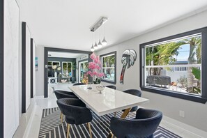 A modern dining area with a white table, black chairs, and a striped rug. - 80’s Paradise golf cart, rooftop deck heated pool (Indian Rocks Beach)