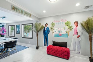 A modern interior with a dining area, a red tufted bench, and a wall mural. - 80’s Paradise golf cart, rooftop deck heated pool (Indian Rocks Beach)