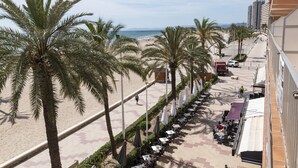Een promenade aan het strand met palmbomen, terrasjes en uitzicht op het strand en de zee.