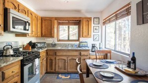 Una cocina con armarios de madera, una estufa y un comedor con una mesa dispuesta para dos.