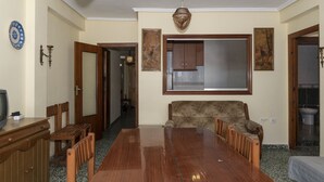 A dining area with a wooden table and chairs, a sofa, and a window with a view of the outside. - LEVANTE, 6º-J (Cullera)