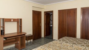 A bedroom with a wooden desk, a bed with a patterned bedspread, and two wooden wardrobes. - LEVANTE, 6º-J (Cullera)