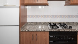 A kitchen with wooden cabinets, a granite countertop, a gas stove, and a dishwasher. - LEVANTE, 6º-J (Cullera)