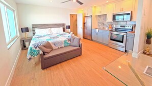 Une chambre moderne dotée d’un grand lit, d’un ventilateur de plafond et d’une kitchenette équipée d’un four à micro-ondes et d’un four traditionnel.