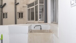 Un baño pequeño y blanco con lavamanos y ventana.