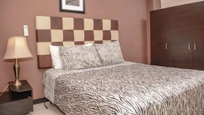 Ein Schlafzimmer mit einem karierten Kopfstück, einer bettenbekleidung mit ZEBRA-Muster, einer Nachttischlampe und einem Kleiderschrank.