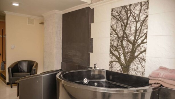 Ein Wellnessbereich mit einer großen Whirlwanne, einem Massagesessel und einer Wandheizung.