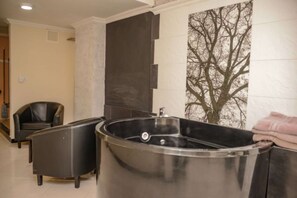 Ein Wellnessbereich mit einer großen Whirlwanne, einem Massagesessel und einer Wandheizung.