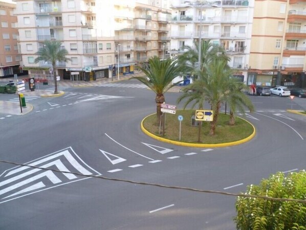 A multi-story residential building with balconies, a roundabout with palm trees, and a road with directional arrows. - ESTIRPE, 2º-3 (Cullera)