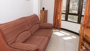 Een kamer met een gestreept sofa, een houten dressoir en een raam met gordijnen.