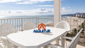 Een witte tafel en stoelen op een balkon met uitzicht op het strand en de oceaan.