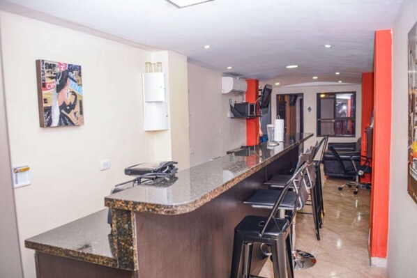 A modern kitchen with a granite countertop, bar stools, and a refrigerator. - Two Bedroom AC hot tub Lleras (Medellin)