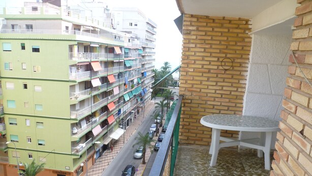 Un balcó amb vista a un carrer, una paret de maó i una taula petita.