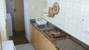 Cuina amb fogó de gas, un rentaplat i armaris. Hi ha una porta que condueix a una altra habitació.