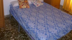 Un dormitori amb un llit, dues almoines i armaris de fusta sobre el llit.