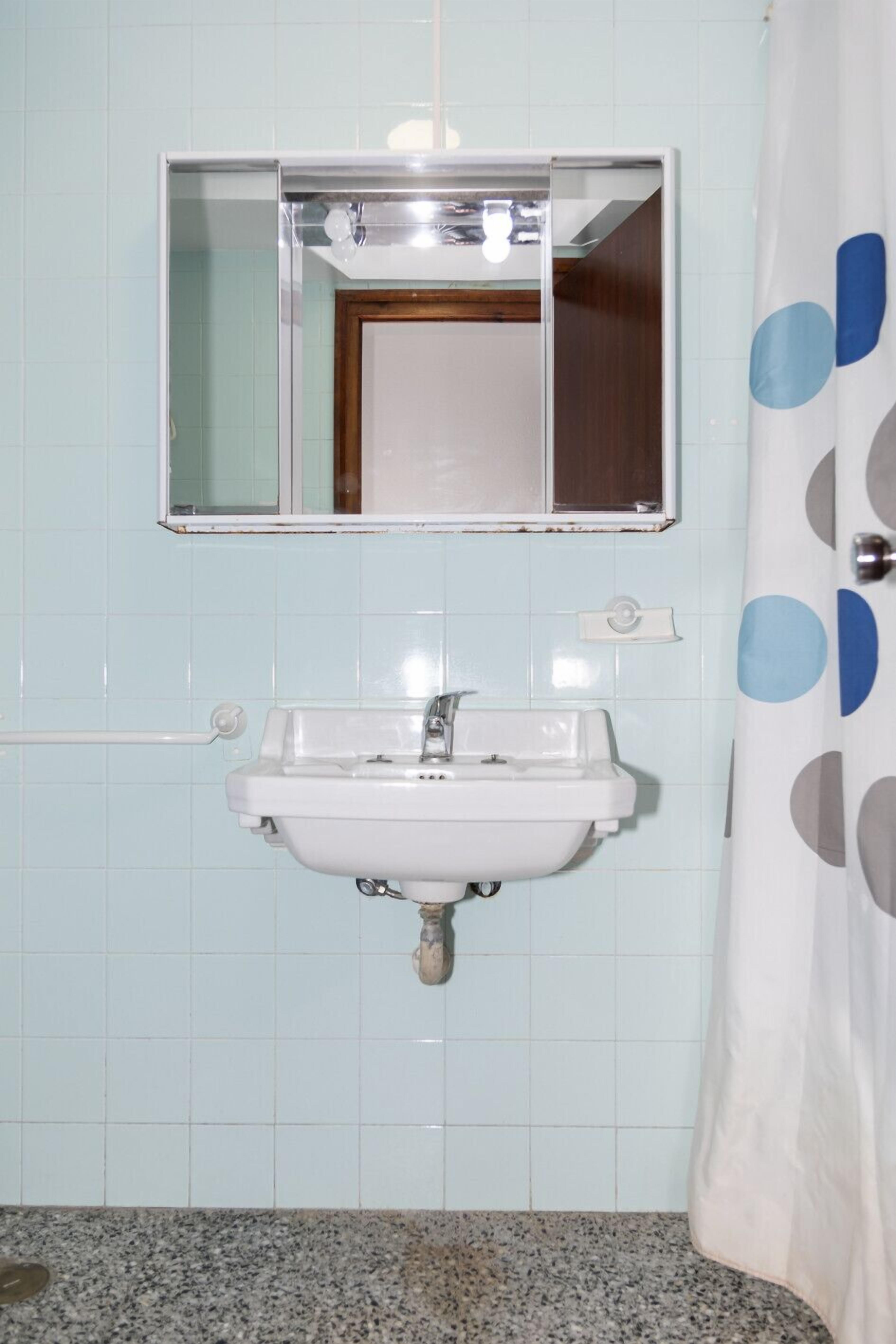 A bathroom with a white sink, a mirror above it, and a shower curtain with a polka dot pattern.