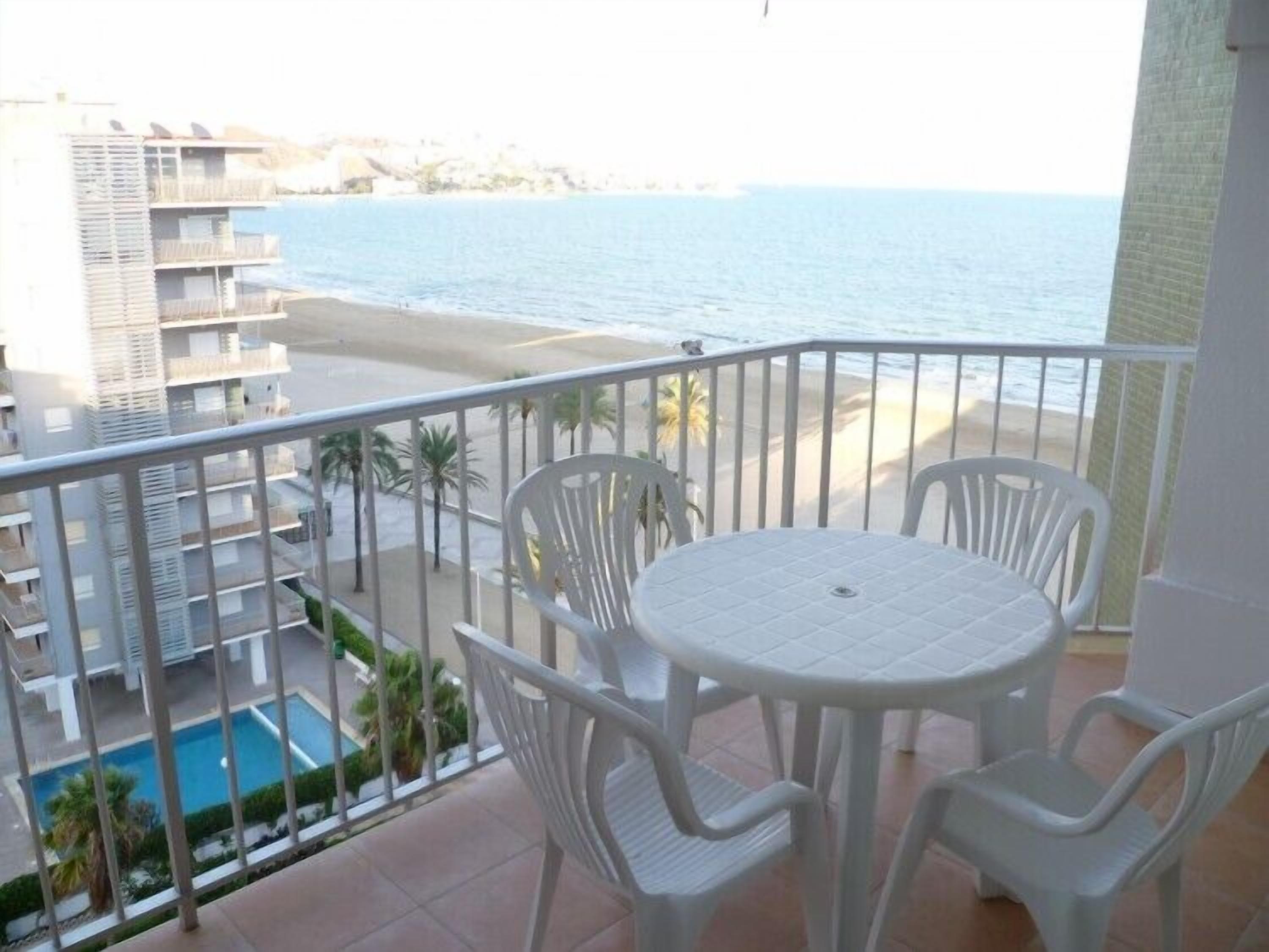 A balcony with a view of the sea and a pool.
