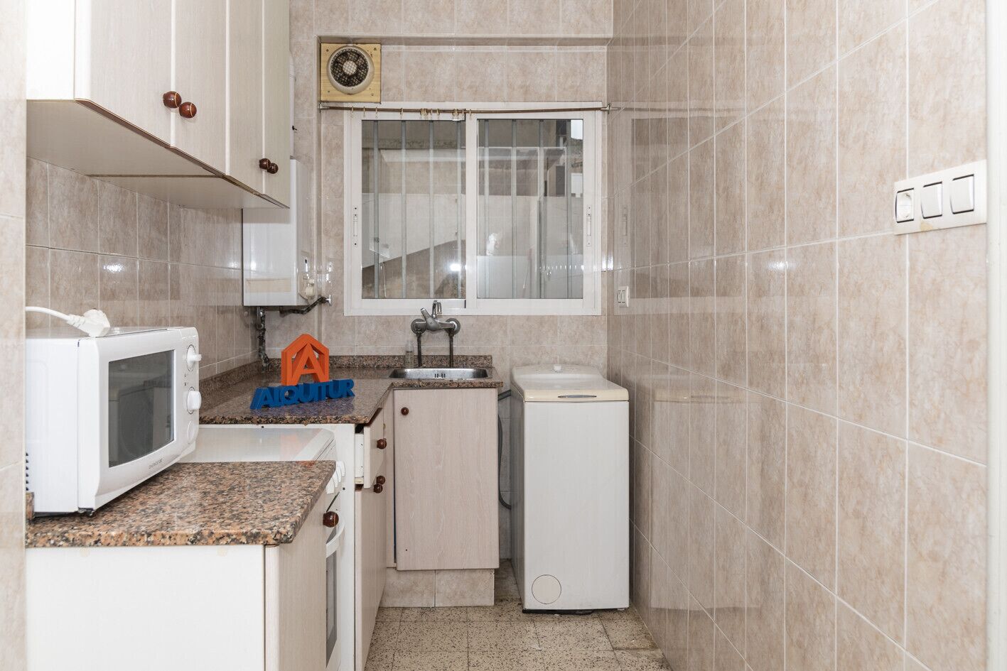 A compact kitchen with a microwave, sink, and small refrigerator.