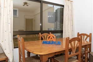 Uma sala de jantar com uma mesa e cadeiras de madeira, uma janela com cortinas e um logotipo na mesa.