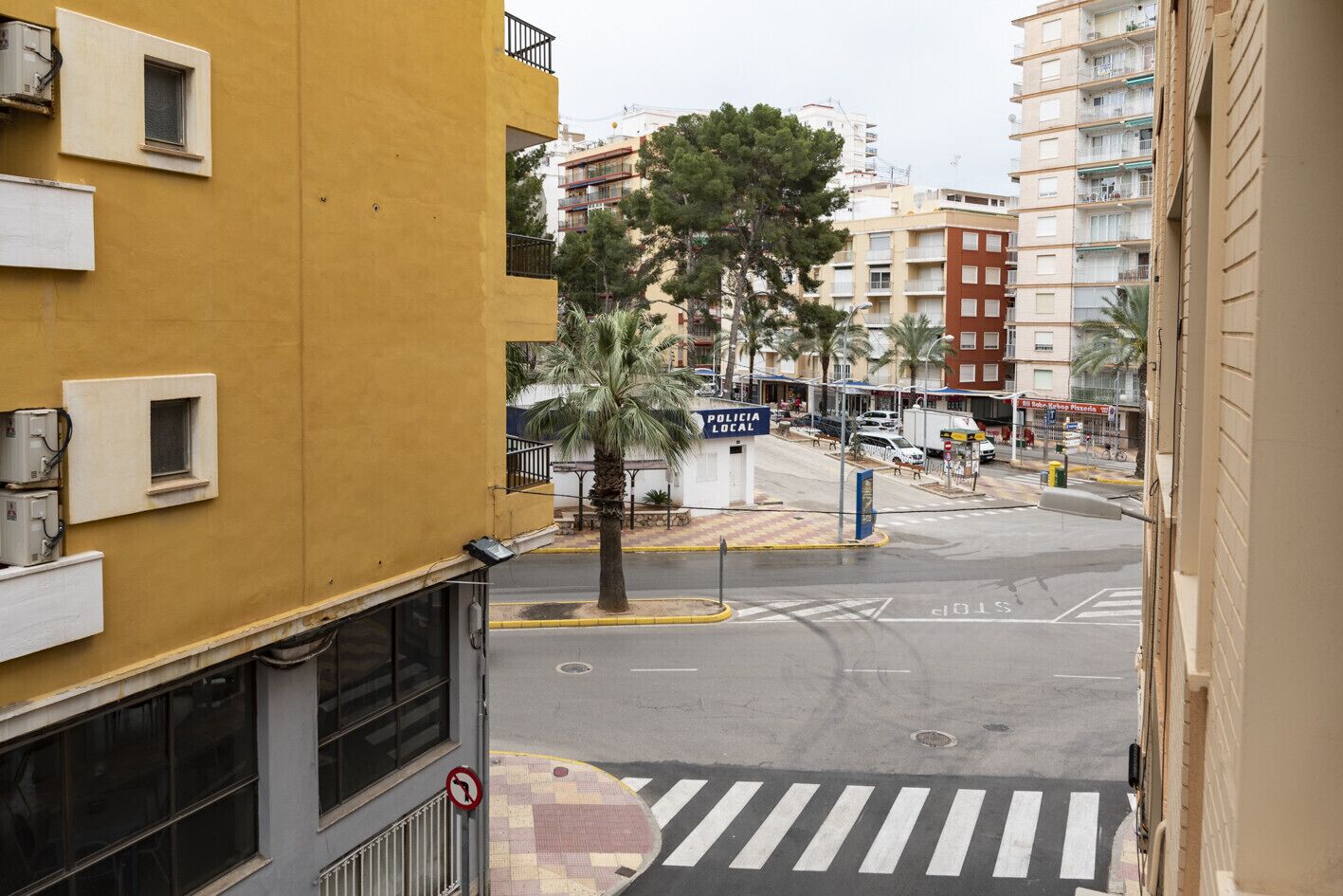 Vista de una calle con un edificio amarillo, una comisaría y un paso de peatones.
