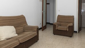 A room with two brown-striped sofas and a chair, a white door, and a tiled floor. - ESTIRPE, 2º-4 (Cullera)