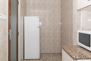 Une petite cuisine équipée d’un réfrigérateur blanc, d’un four à micro-ondes et d’un plan de travail en granit.