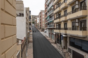 Uma rua estreita flanqueada por edifícios altos, alguns com varandas e aparelhos de ar condicionado.