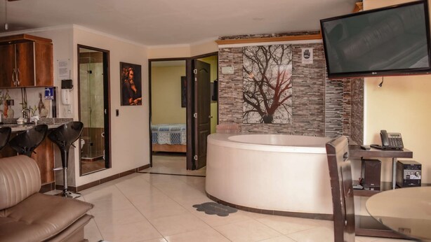 A modern living room with a large TV, a hot tub, and a dining area. - 2 Bedroom Hot tub security AC Lleras area (medellin)