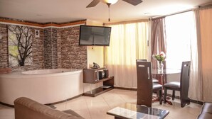 A modern living room with a large flat-screen TV, a ceiling fan, a bathtub, and a dining area with chairs and a table. - 2 Bedroom Hot tub security AC Lleras area (medellin)