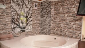 A bathroom with a large bathtub, a wall-mounted TV, and a tree mural. - 2 Bedroom Hot tub security AC Lleras area (medellin)