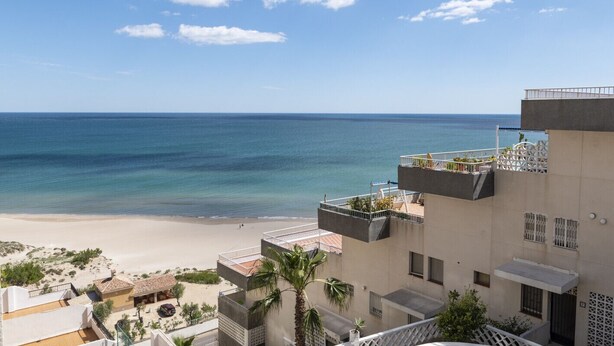 A beachfront hotel with multiple balconies overlooking the sea, a sandy beach, and clear skies. - DOSEL, 6º-30 PARKING 30 (Faro de Cullera)