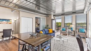 A spacious living area with a kitchen island, seating area, and large windows offering views. - Urban Condo with Balcony in Downtown Ann Arbor (Ann Arbor)