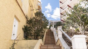 Uma escadaria leva a um edifício com uma porta branca e uma varanda.