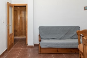 Une pièce avec une porte en bois, un canapé gris et une chaise en bois.