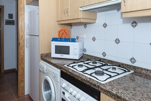 A compact kitchen with a microwave, stove, and washing machine.