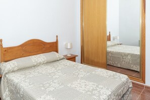 A bedroom with a wooden bed, a nightstand, a mirror, and a wardrobe. - PLENO SOL, 45 (Faro de Cullera)