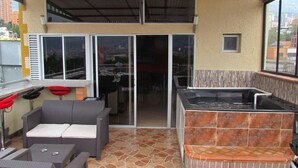 An outdoor patio with a grill, seating area, and a hot tub.