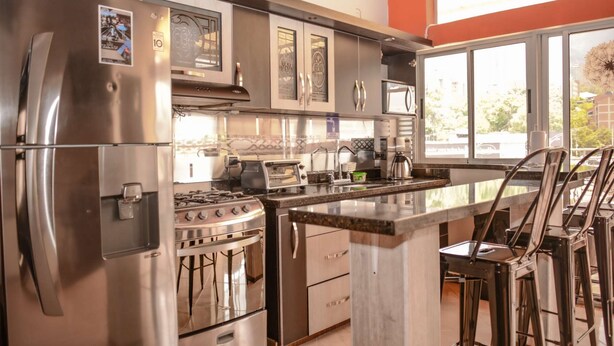 A modern kitchen with stainless steel appliances, a gas stove, and a bar area with stools.