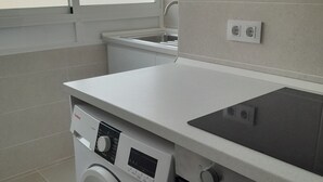 Una cocina compacta con lavadora, horno, lavaplatos y ventana.