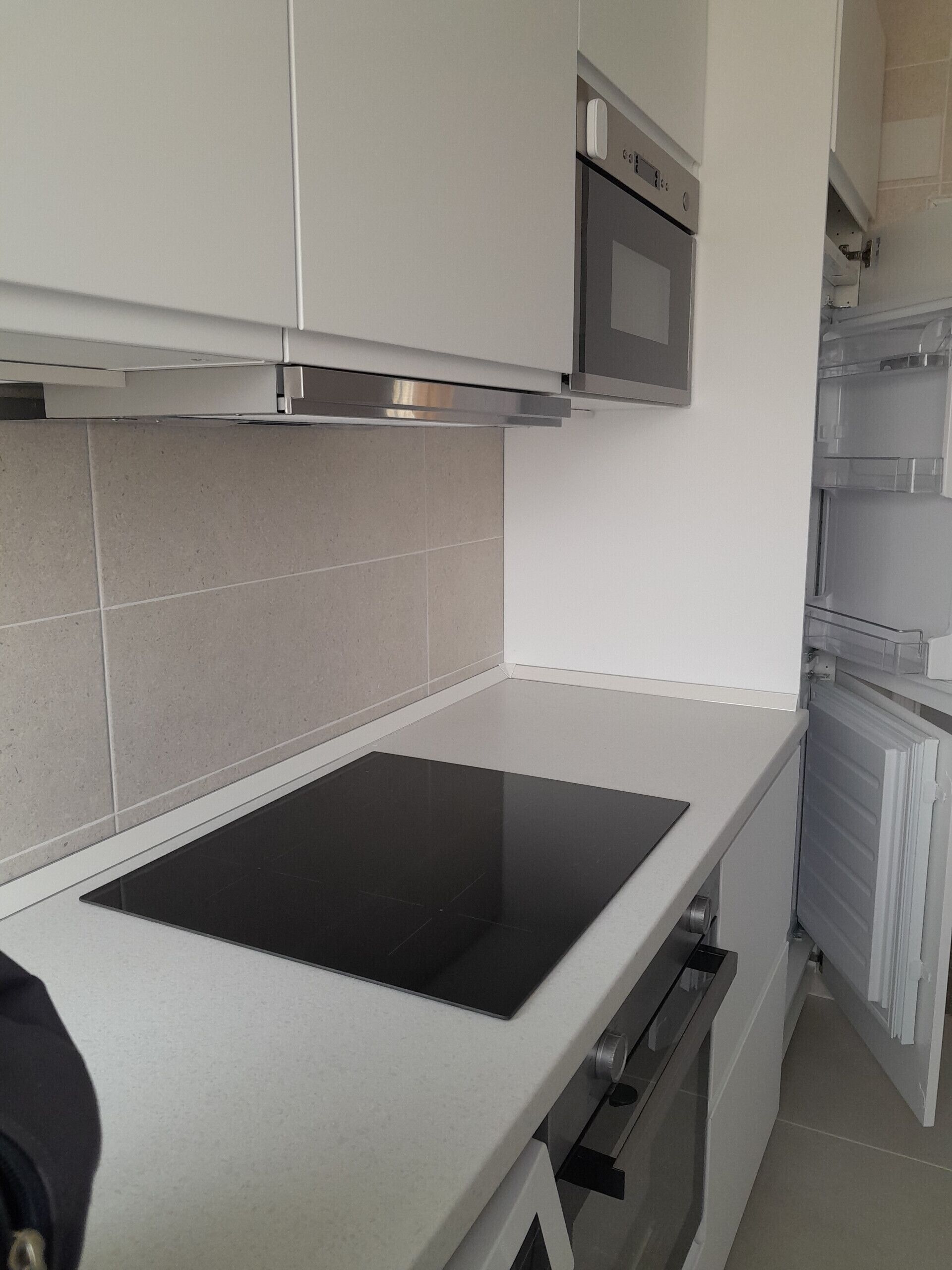 A kitchen with white cabinets, a black countertop, a built-in oven, and a microwave.