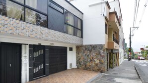 A modern building with a tiled facade, a stone wall, and a black gate. - One Bedroom Loft AC Hot Tub APT 201 (Medellin)
