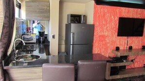 A modern kitchen with a refrigerator, microwave, and a flat-screen TV mounted on the wall. - One Bedroom Loft AC Hot Tub APT 201 (Medellin)