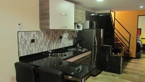 Eine moderne Küche mit schwarzem Arbeitsplatz, Edelstahlgeräten und einer Holzrückwand.