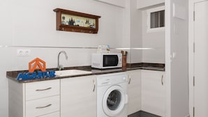 A modern kitchen with a built-in washing machine, a microwave, and a sink. - MAR Y MONTAÑA 7º-119 (Cullera)