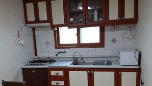 Una cocina con armarios de madera, estufa a gas, pileta y microondas.